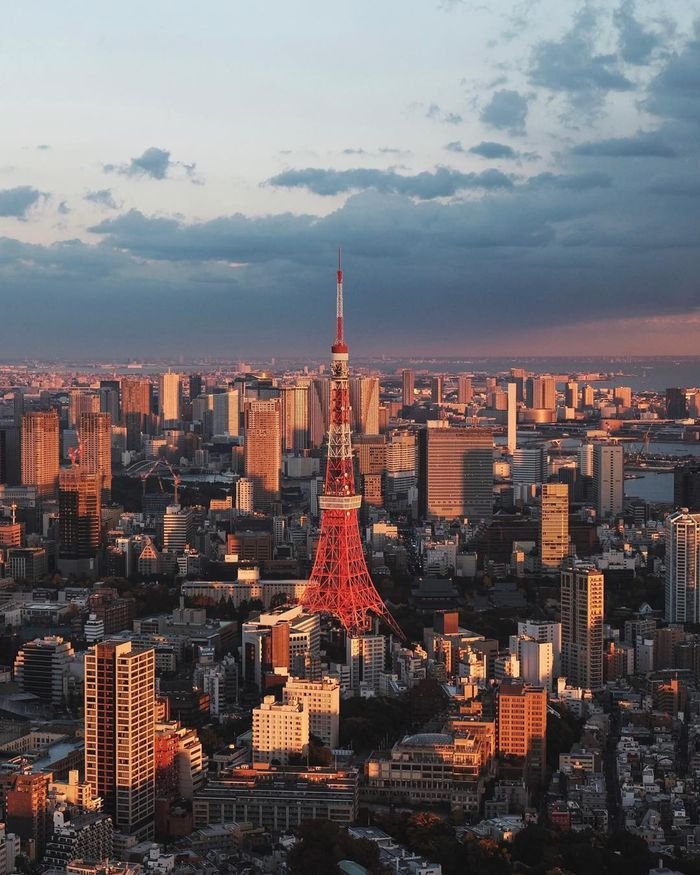 Stunning aerial view of Tokyo Tower with the cityscape under a dramatic sunset sky.